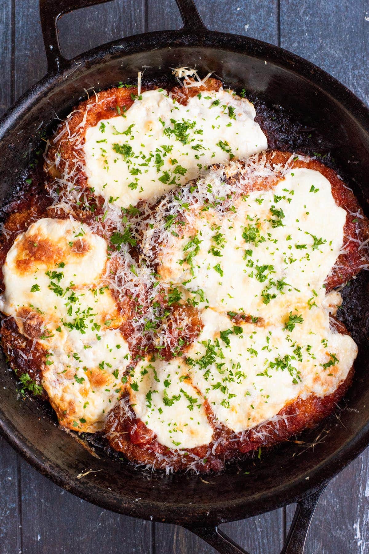 Cheesy baked chicken parmesan in a cast iron skillet.
