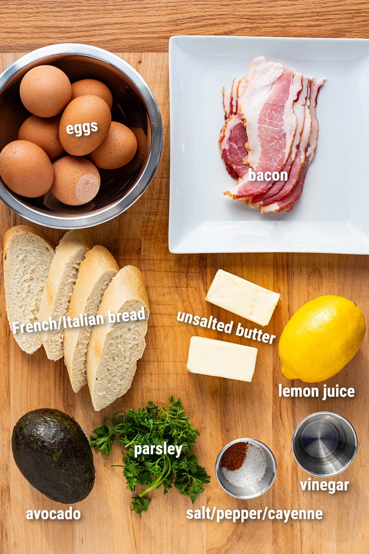 Raw, uncooked Eggs Benedict ingredients laid out on a wooden cutting board.