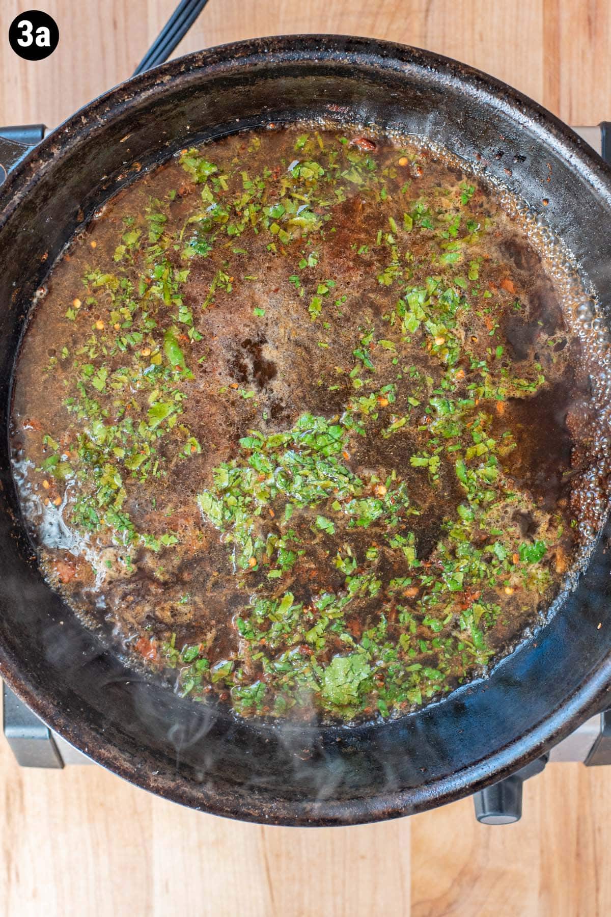 Uncooked cilantro lime marinade starting to simmer in a cast iron skillet.