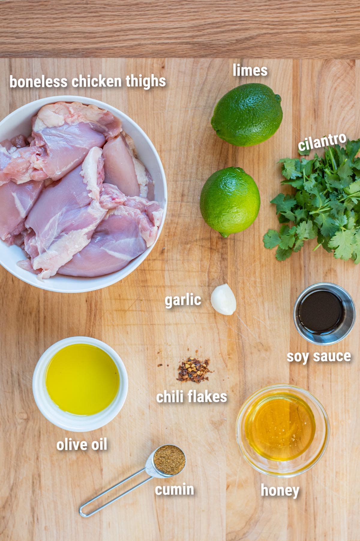 Raw, uncooked cilantro lime chicken ingredients laid out on a wooden cutting board.