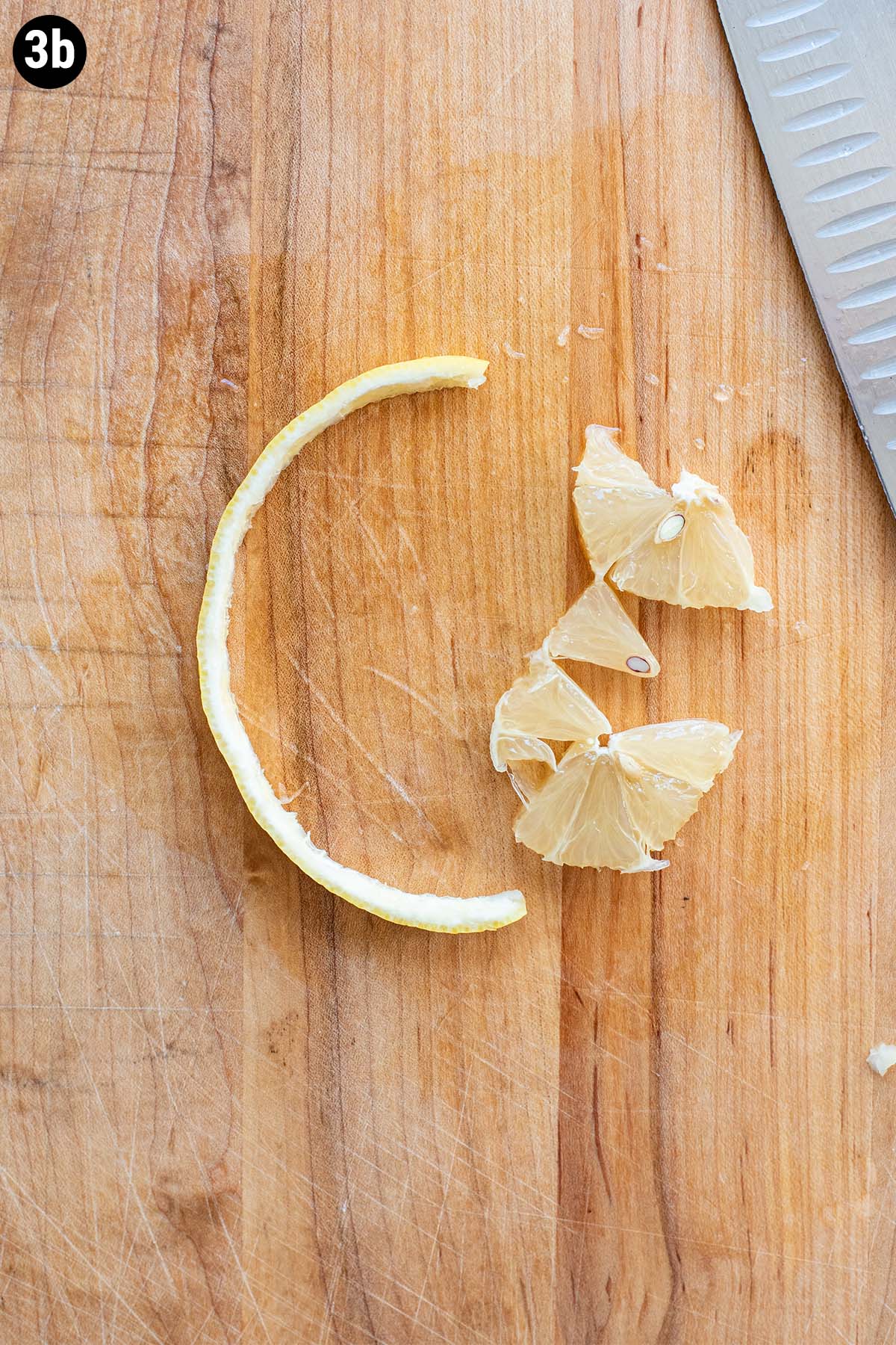A lemon wheel peel with the flesh removed on a wooden cutting board.