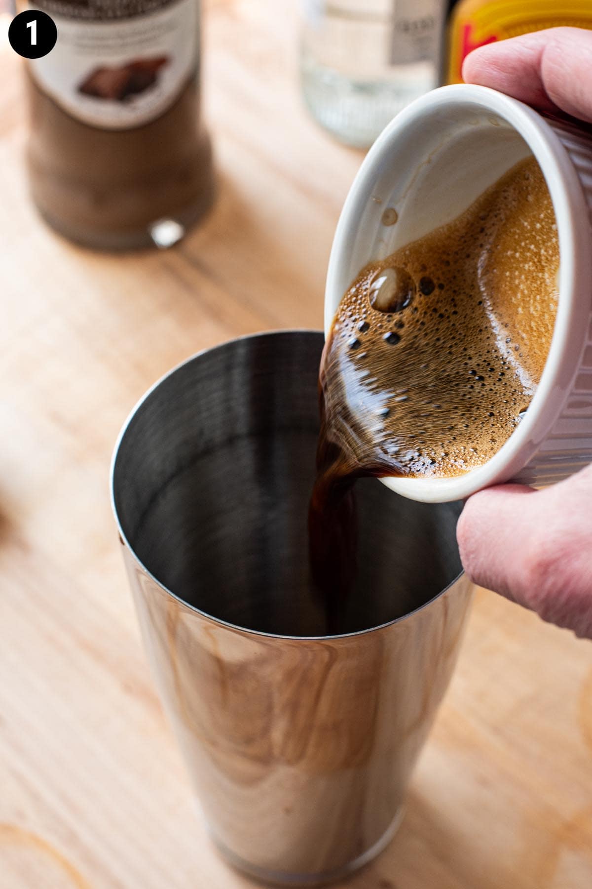 Pouring espresso into a cocktail shaker.