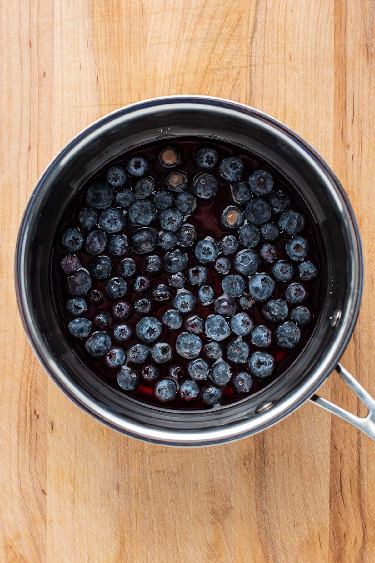 Whole fresh blueberries, red wine, sugar, and salt in a stainless saucepan.