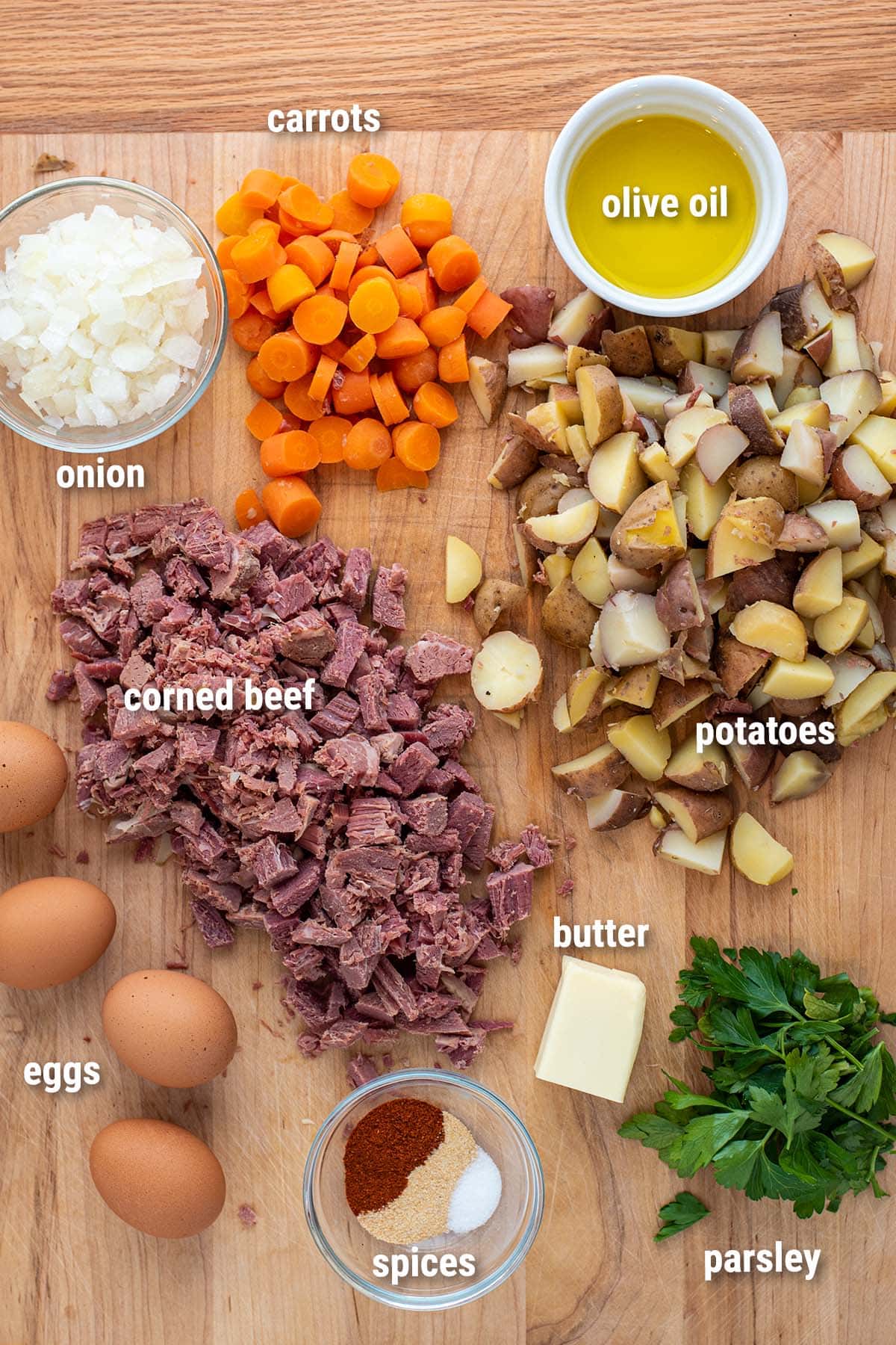 Diced precooked ingredients for corned beef hash laid out on a wooden cutting board.