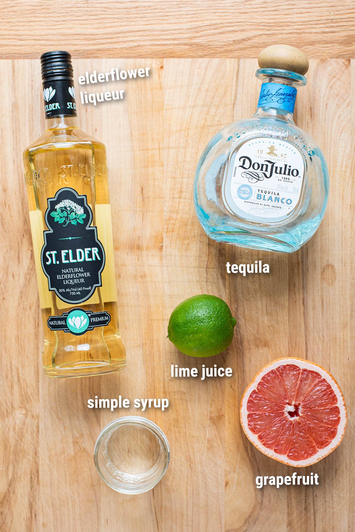 Grapefruit margarita cocktail ingredients laid out on a wooden cutting board.