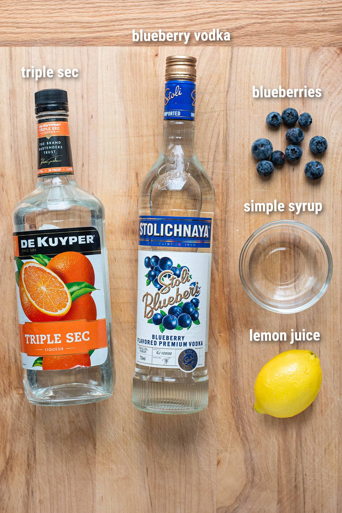 Blueberry martini ingredients laid out on a wooden cutting board.