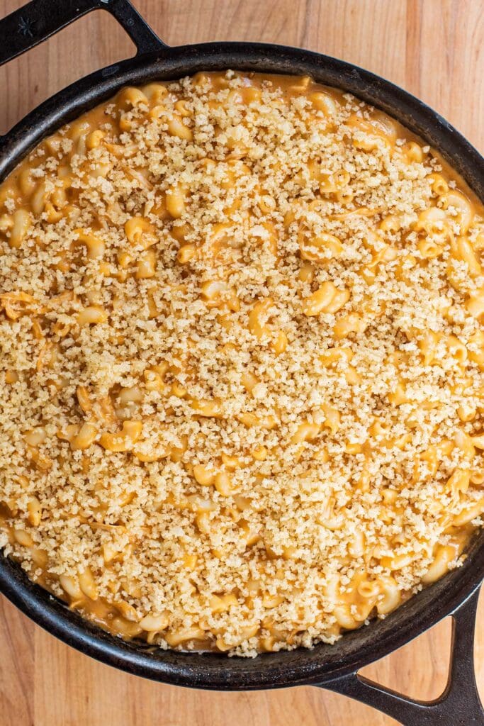Panko crumbs topped over unbaked macaroni and cheese in a cast iron skillet.