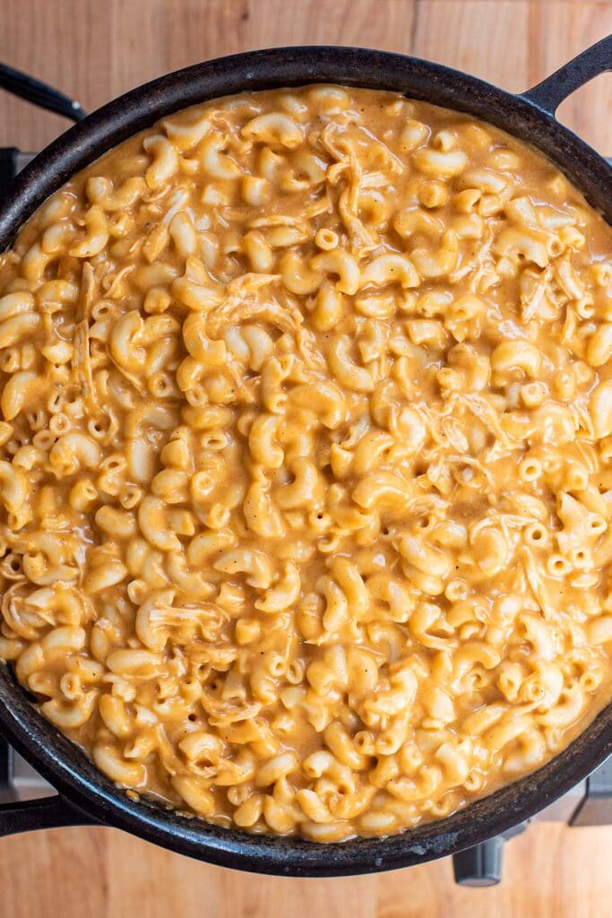 Buffalo chicken mac and cheese in a cast iron skillet before baking with breadcrumbs.