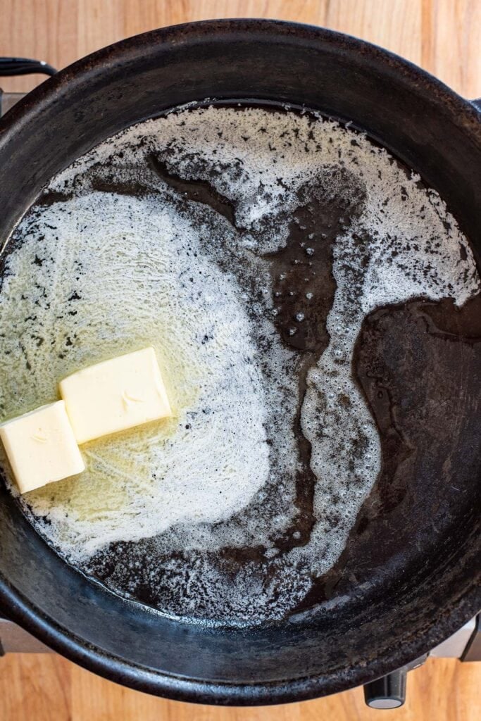 Butter slowly melting in a cast iron skillet.