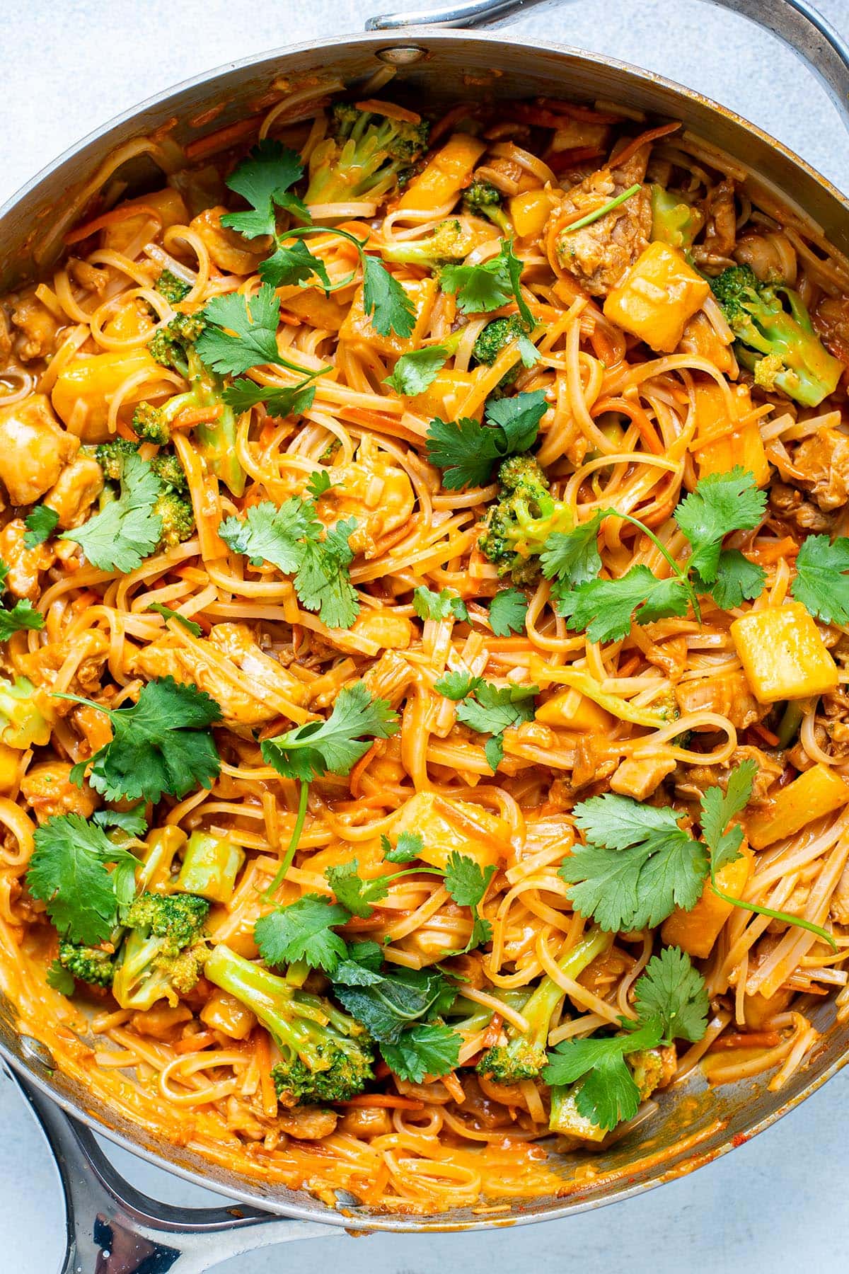 Coconut curry rice noodles served with chicken, broccoli, cilantro, and pineapple.
