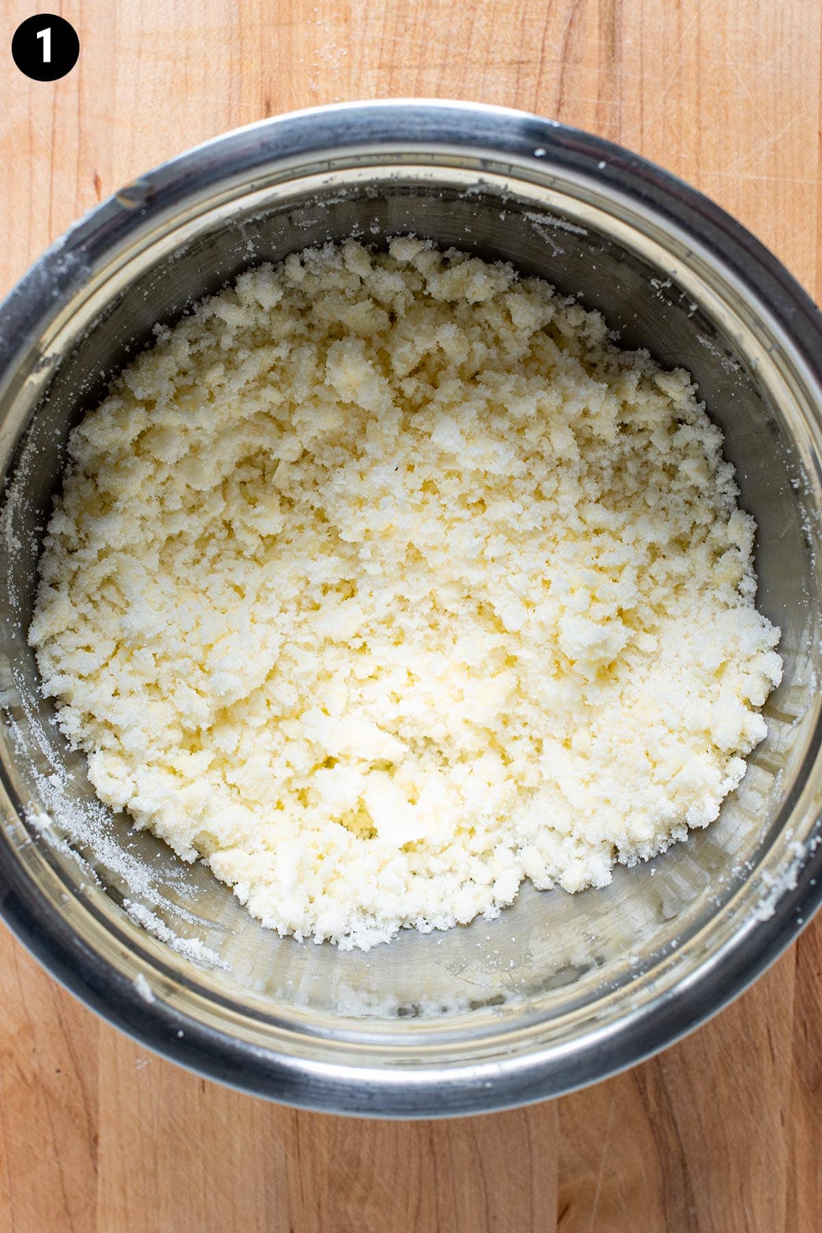 Sugar and creamed butter in a stainless steel bowl.