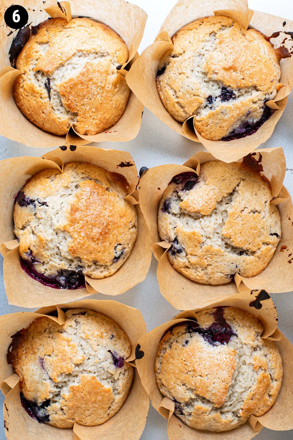 Perfectly golden baked blueberry muffins in a muffin tin.