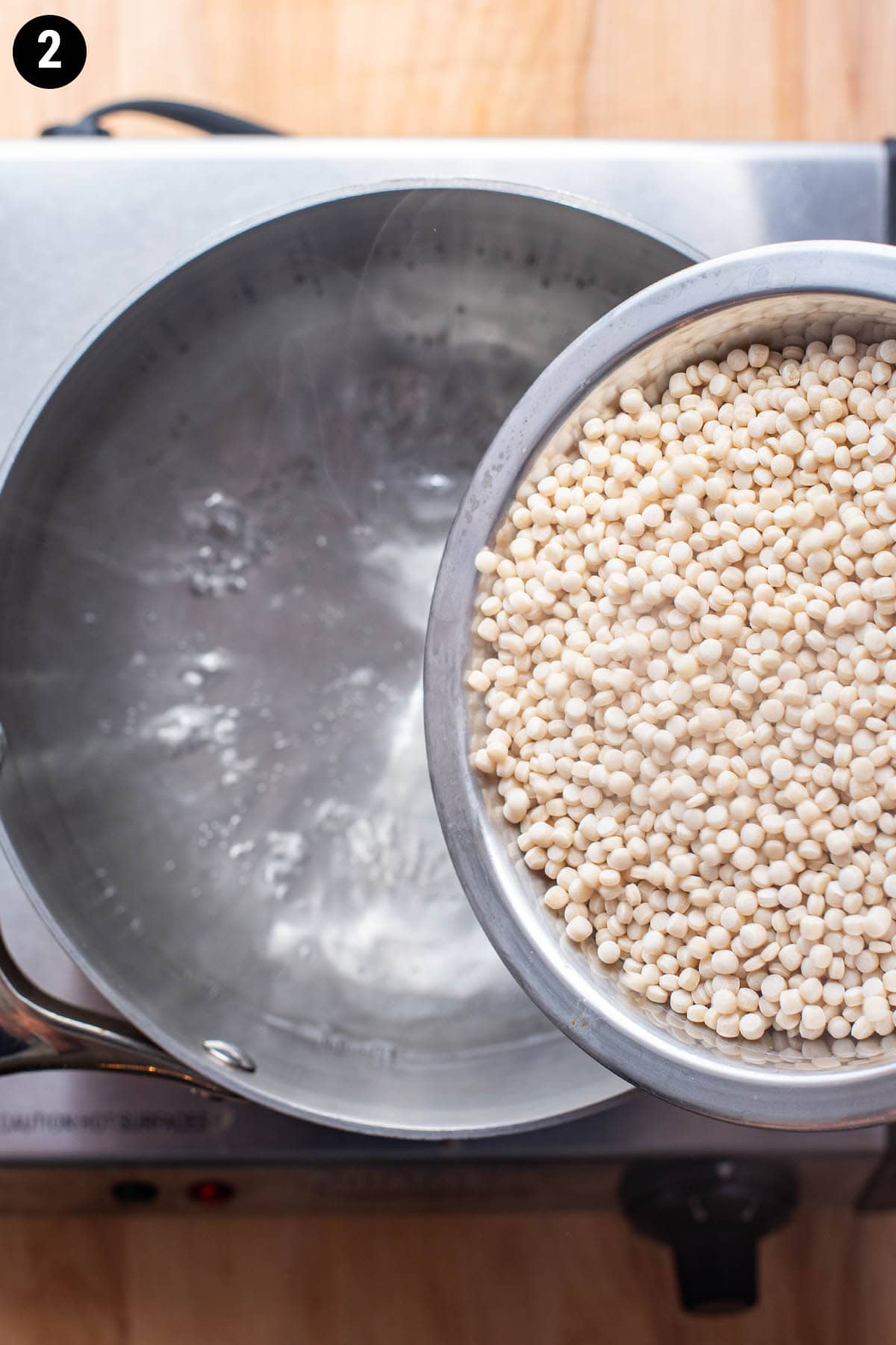 Pouring pearl couscous into boiling water.