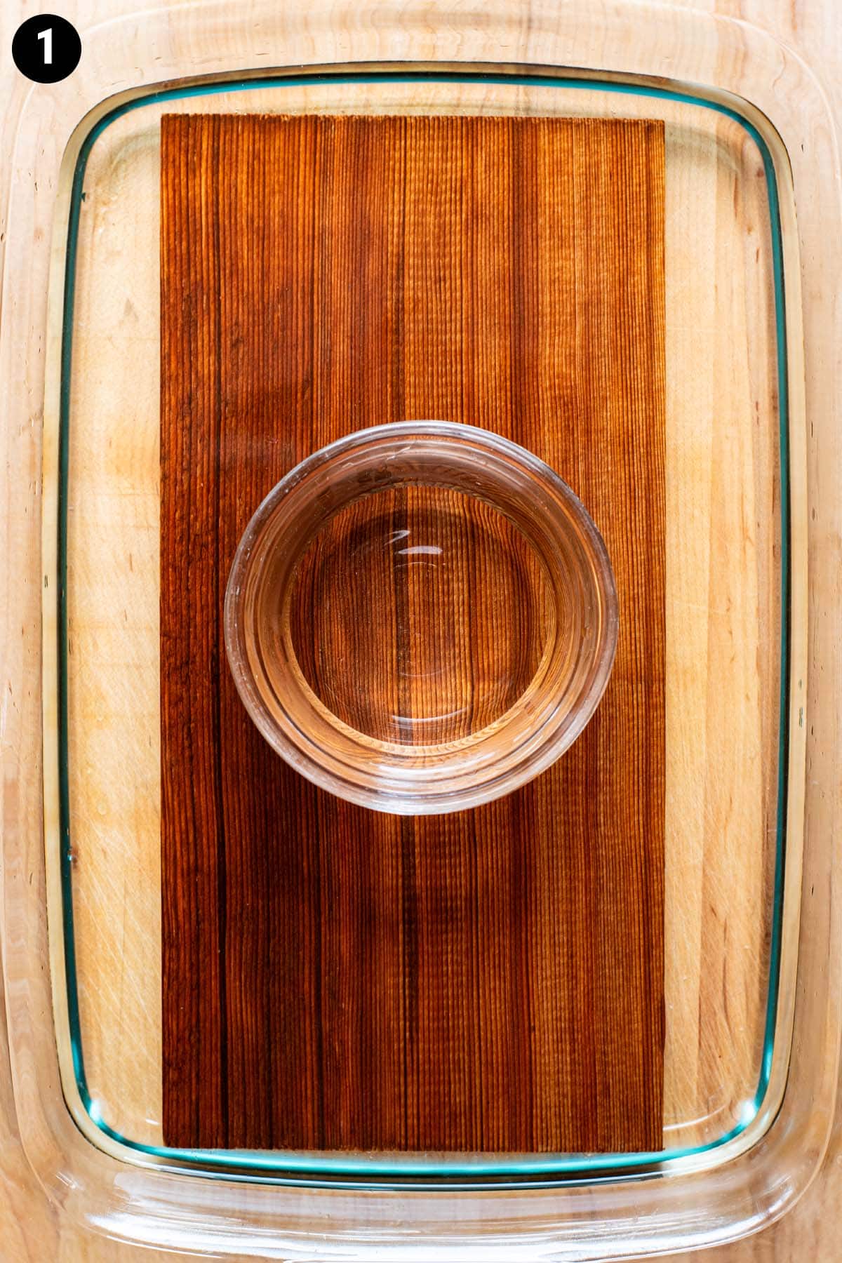 A cedar plank, used for grilling, soaking in water on the counter.