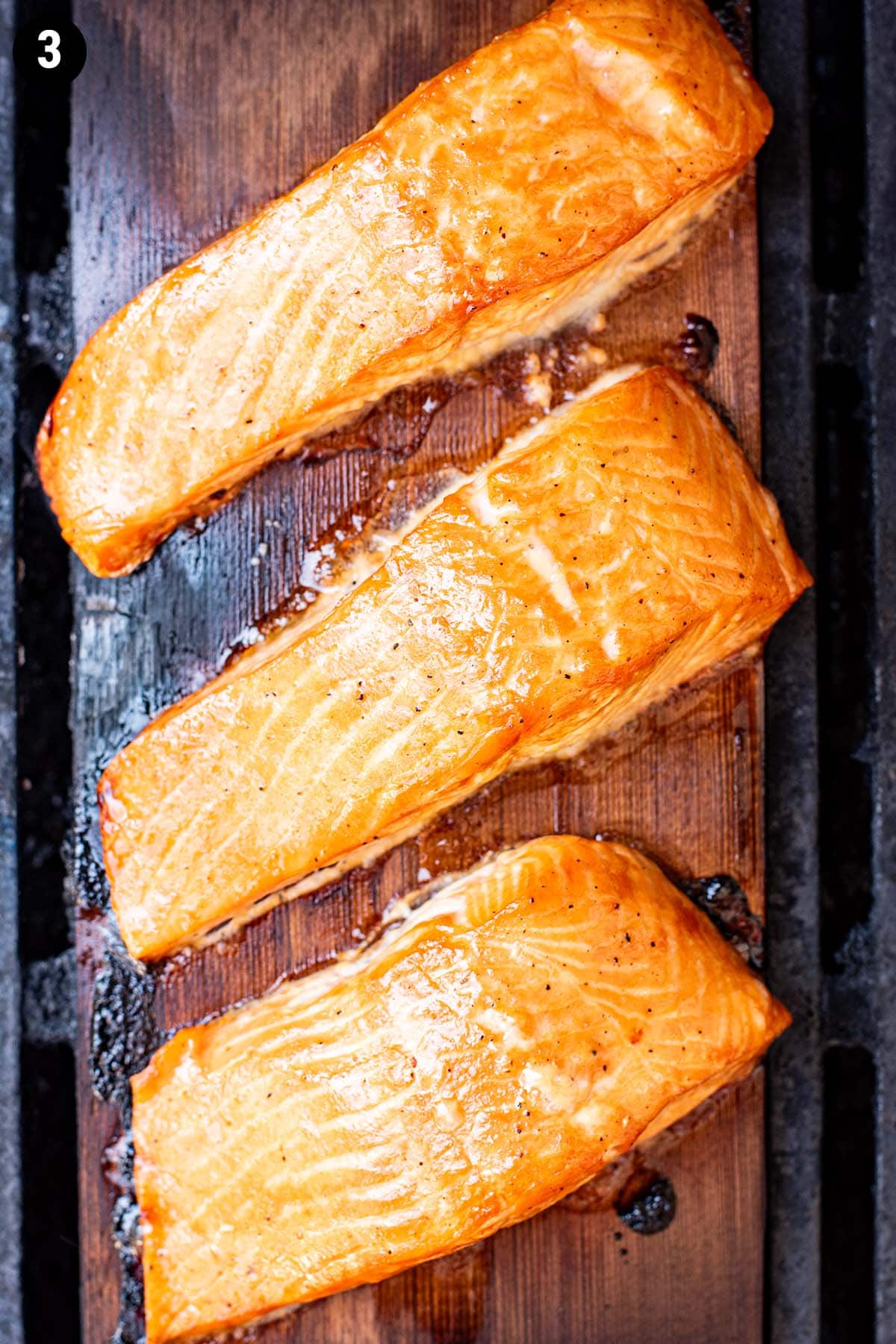 Cedar plank salmon cooking on a grill.