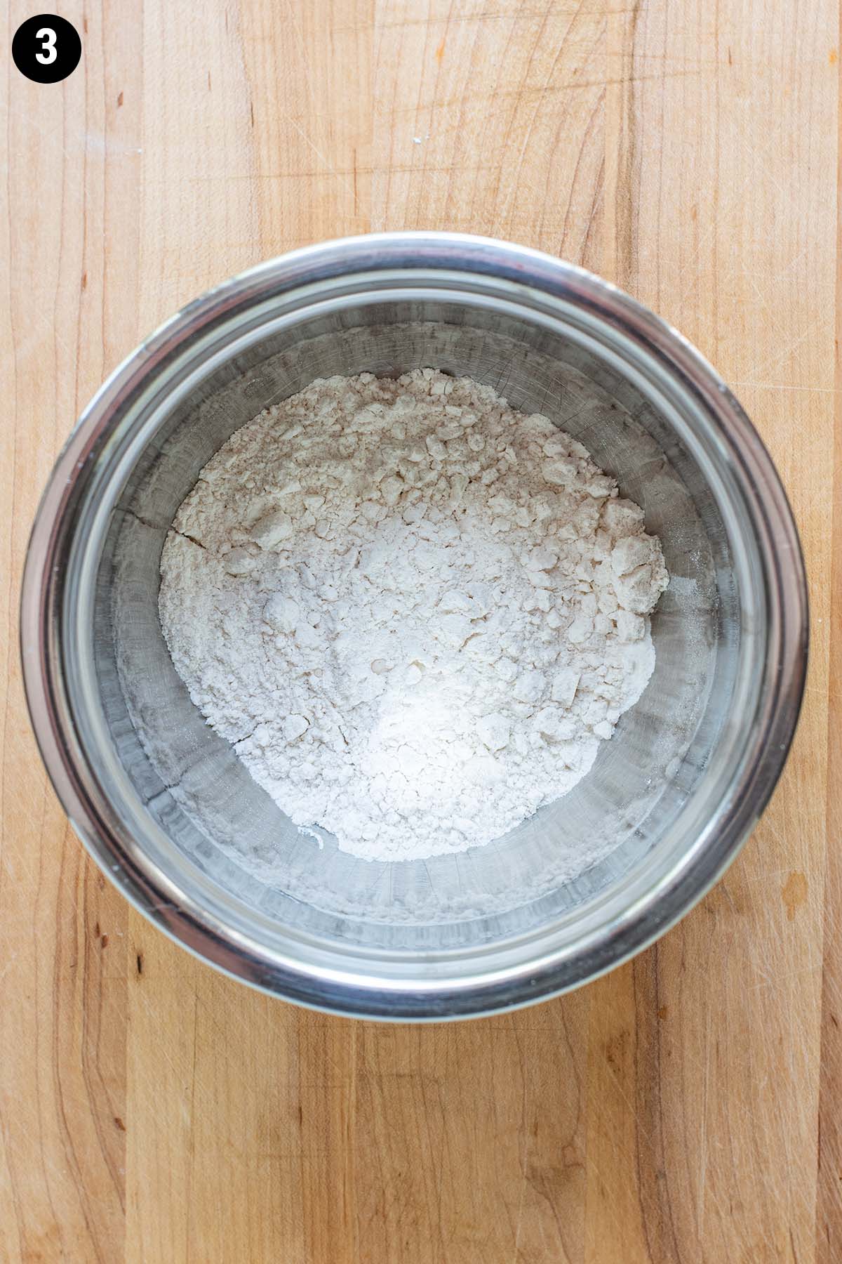Flour and baking powder in a small stainless steel bowl.
