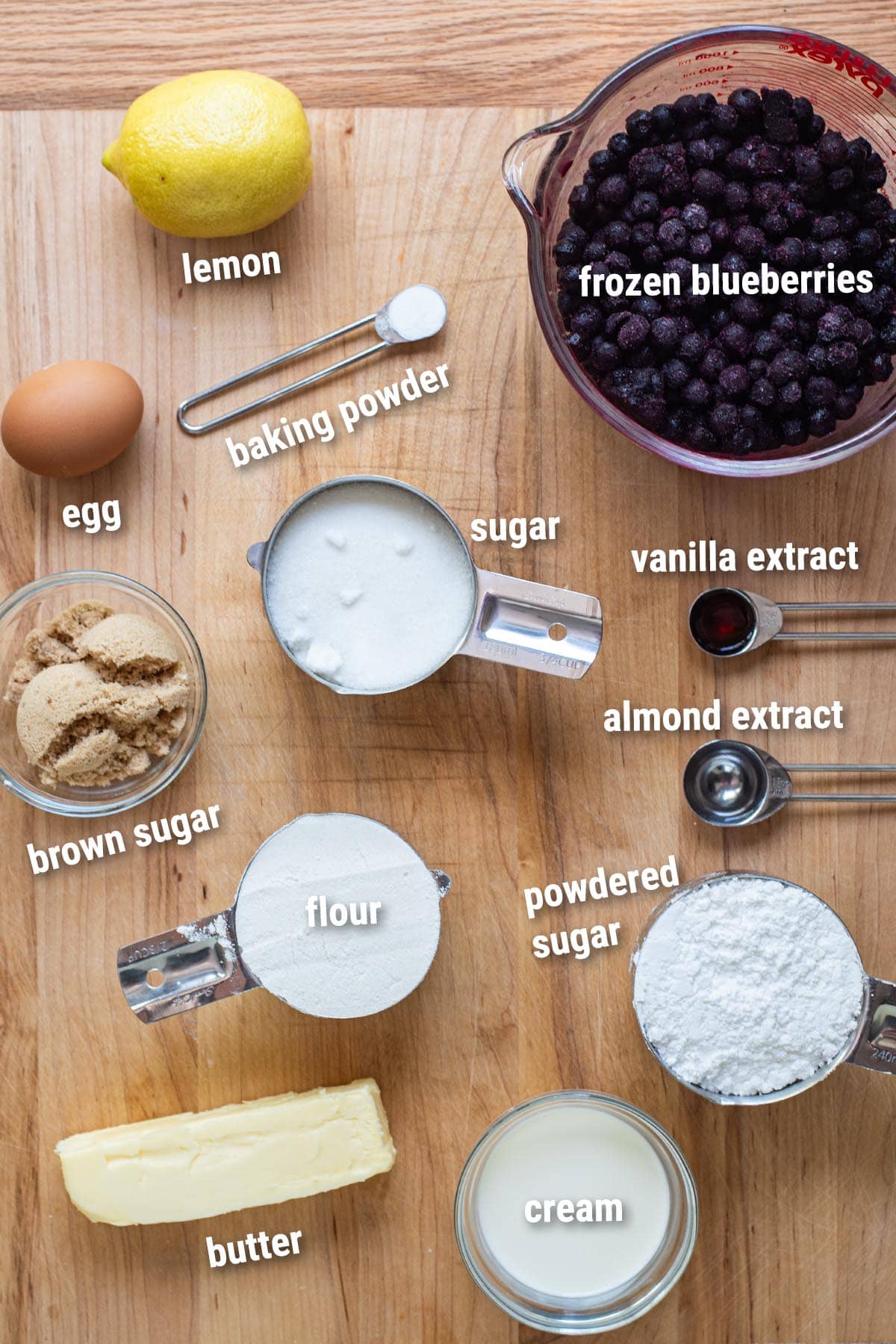 Raw, uncooked skillet blueberry cobbler ingredients on a wooden cutting board.