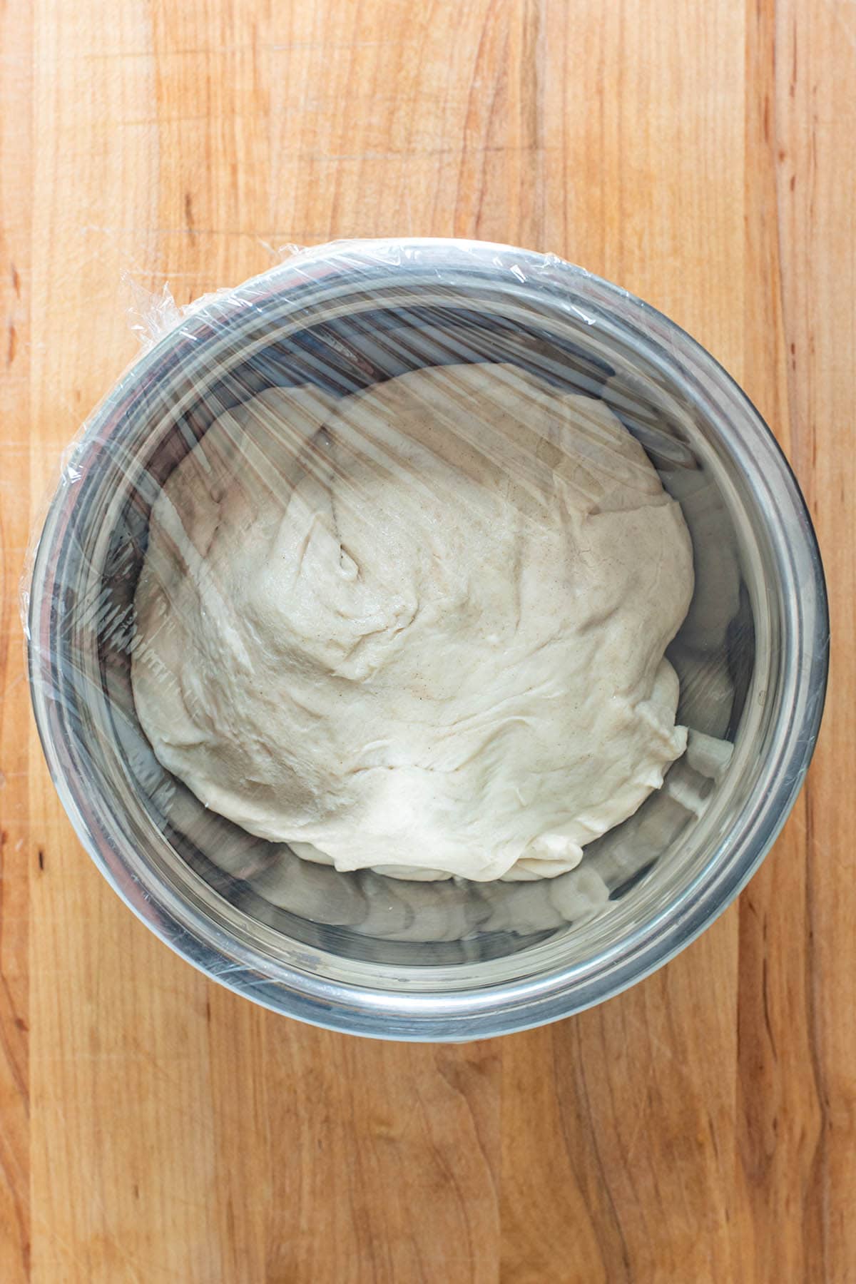 Cold pizza dough in a stainless steel bowl.