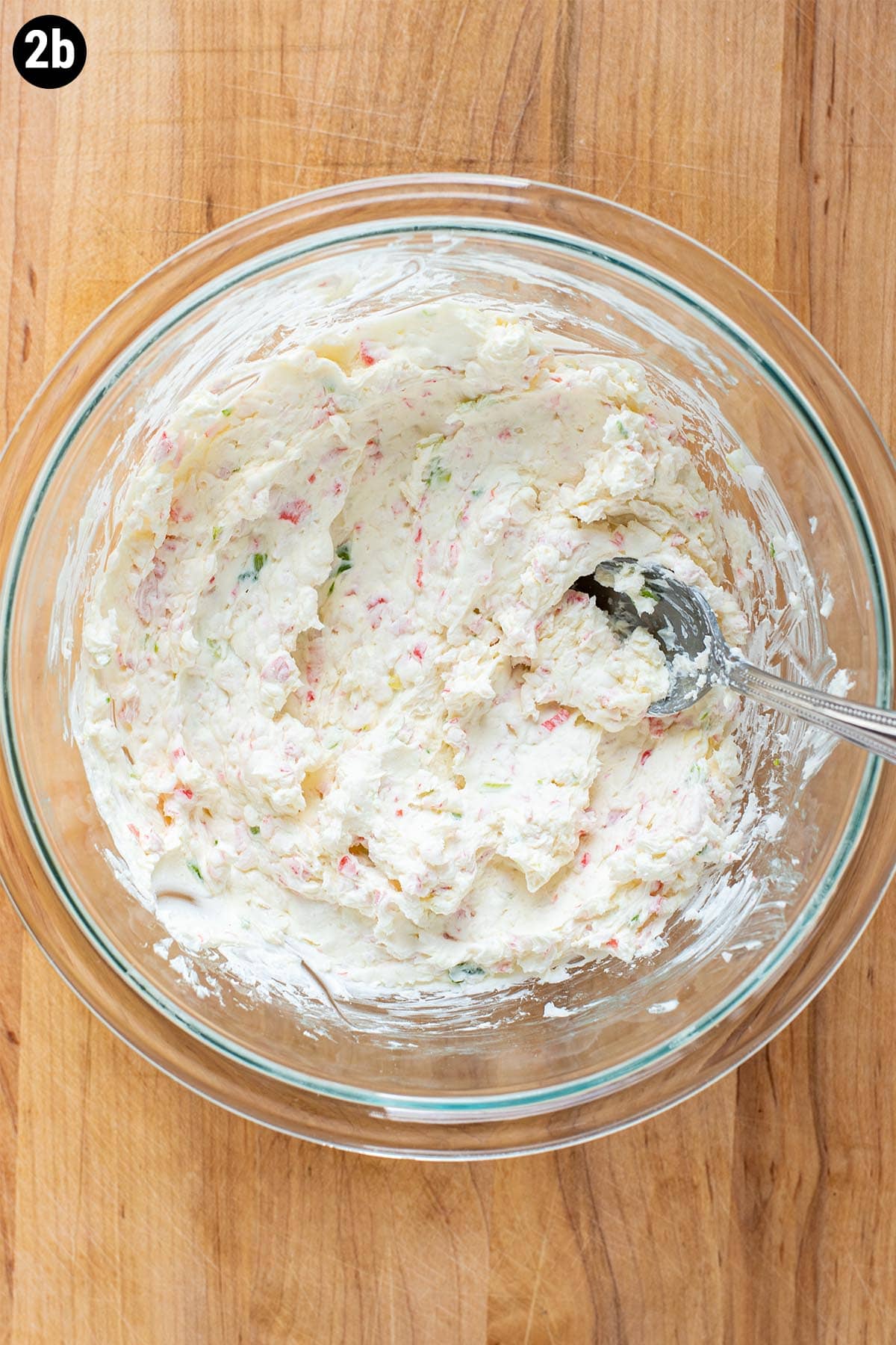 Cream cheese, diced imitation crab, and diced white onion mixed in a small bowl for rangoon filling.