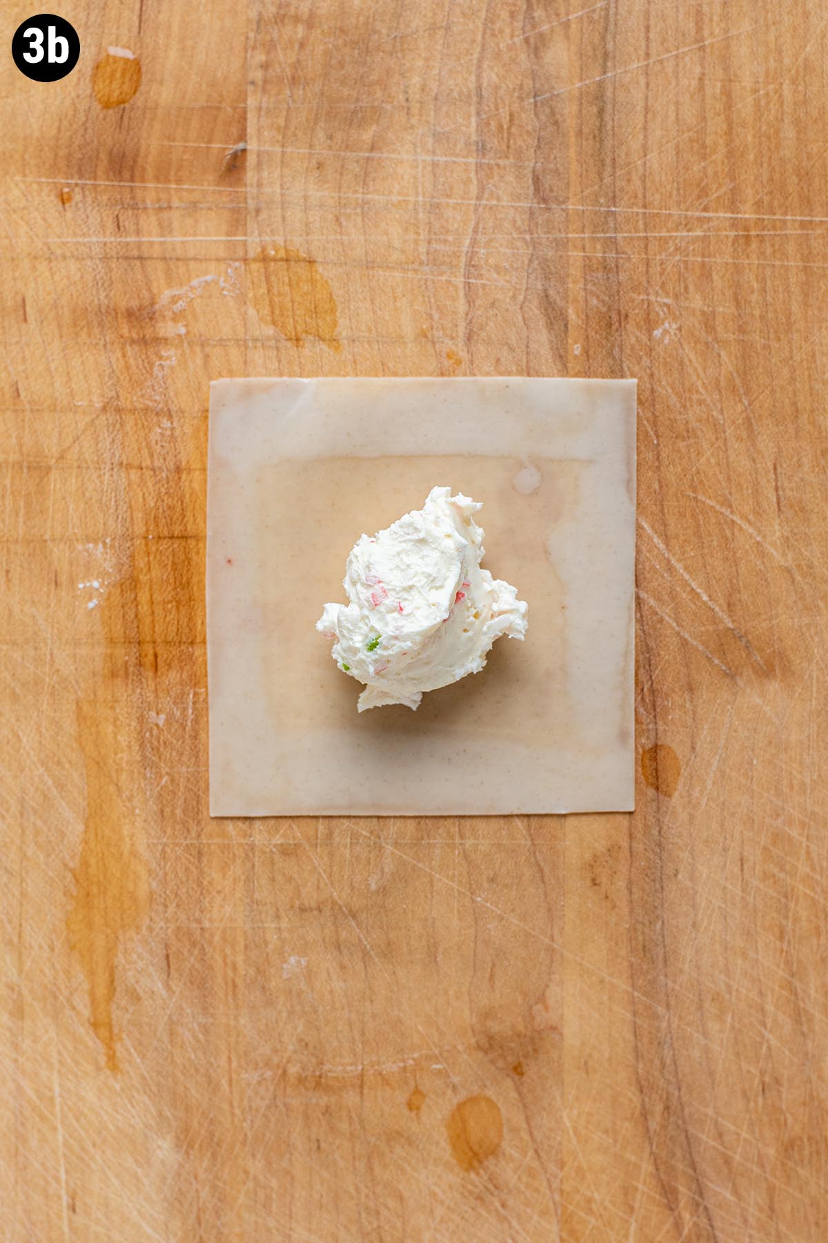 A dollop of cream cheese filling in the center of an unwrapped wonton wrapper.