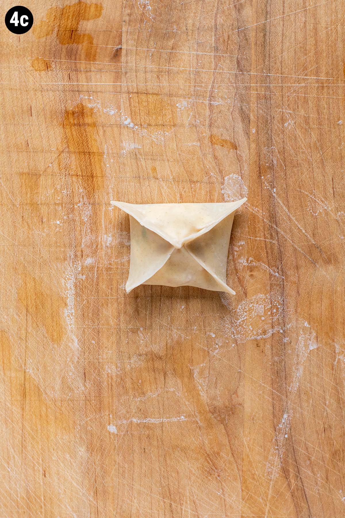 A finished, uncooked crab rangoon that's been folded into a sqaure.