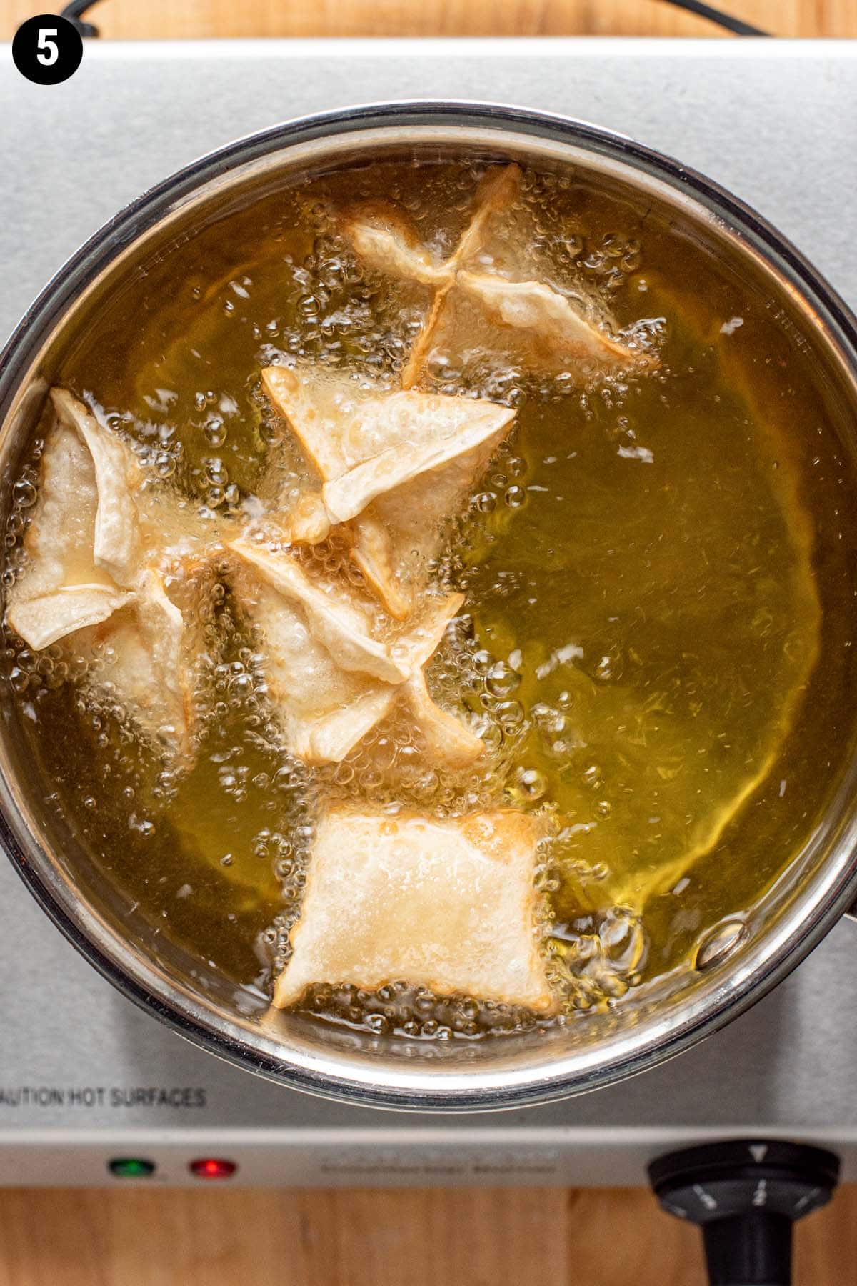 Deep frying crab rangoons in sizzling hot oil.