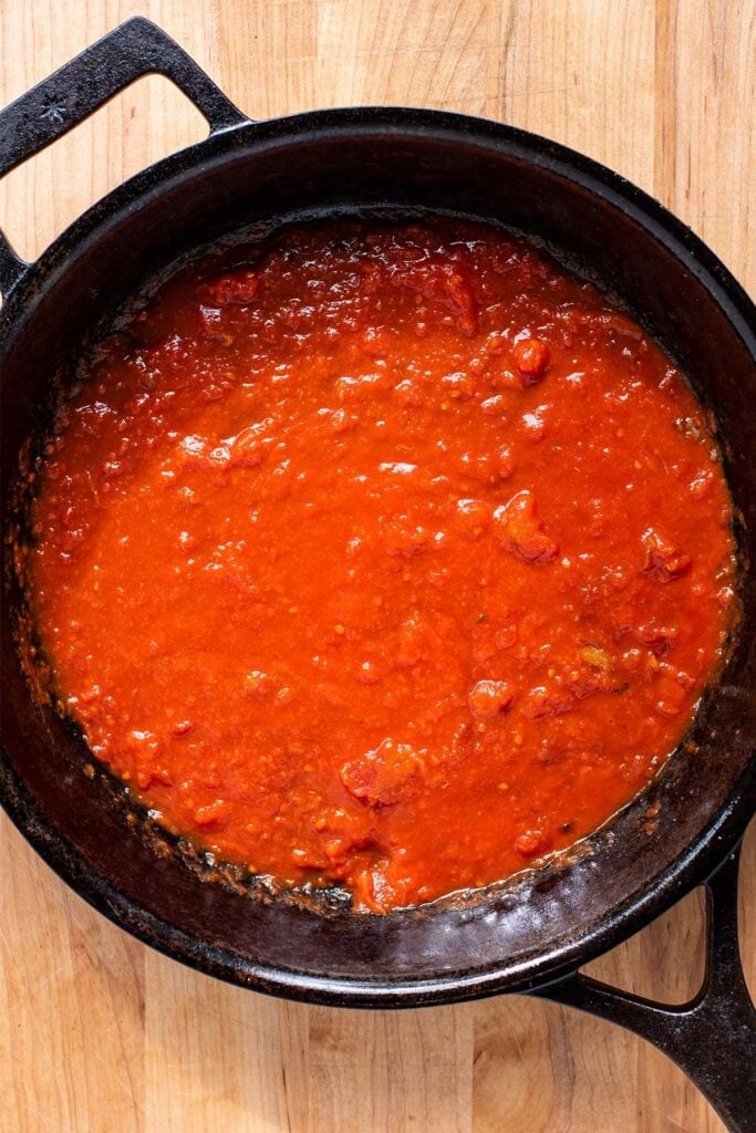 A thin later of marinara in a cast iron skillet.