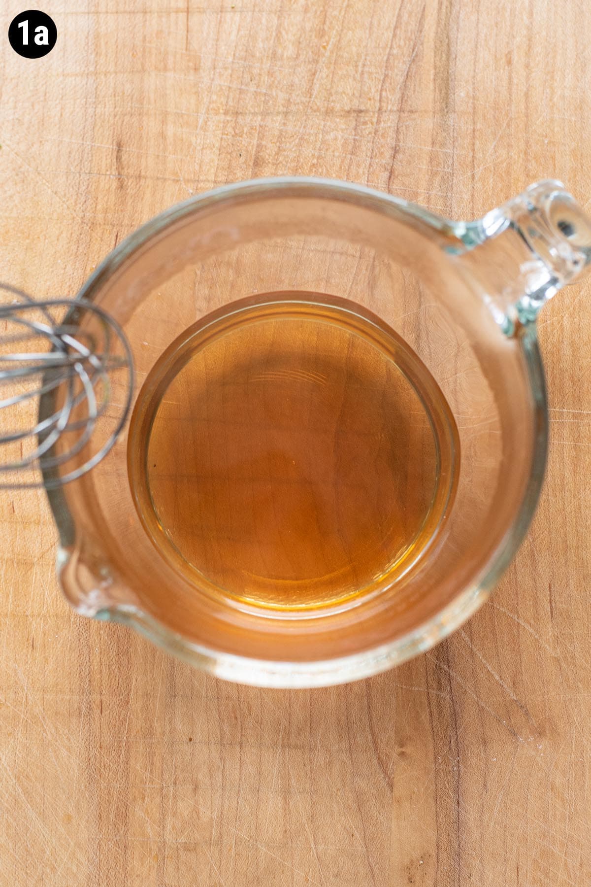 Brown sugar dissolved in hot water in a glass measuring cup.