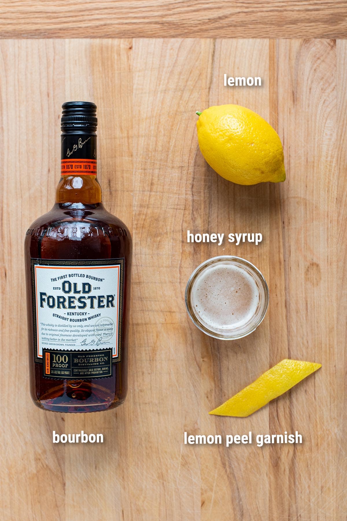 Gold Rush cocktail ingredients laid out on a wooden cutting board.
