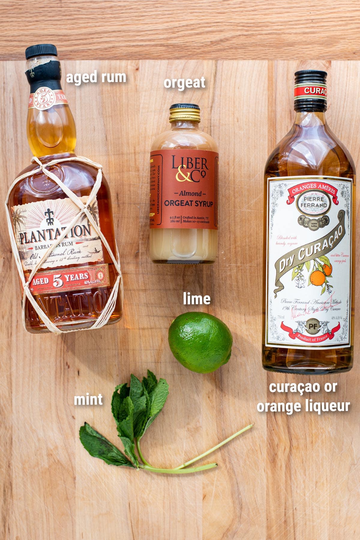 Classic Mai Tai ingredients laid out on a wooden cutting board.
