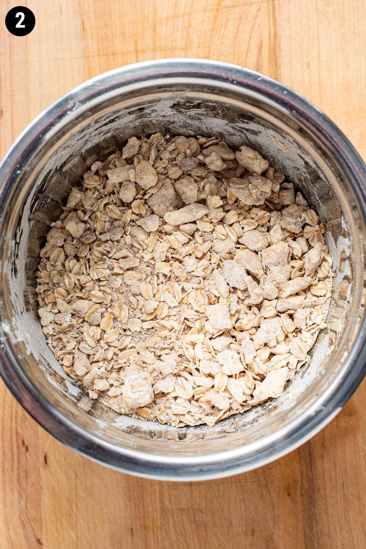 Brown sugar, flour, oats, and butter mixed together in a small stainless steel bowl.