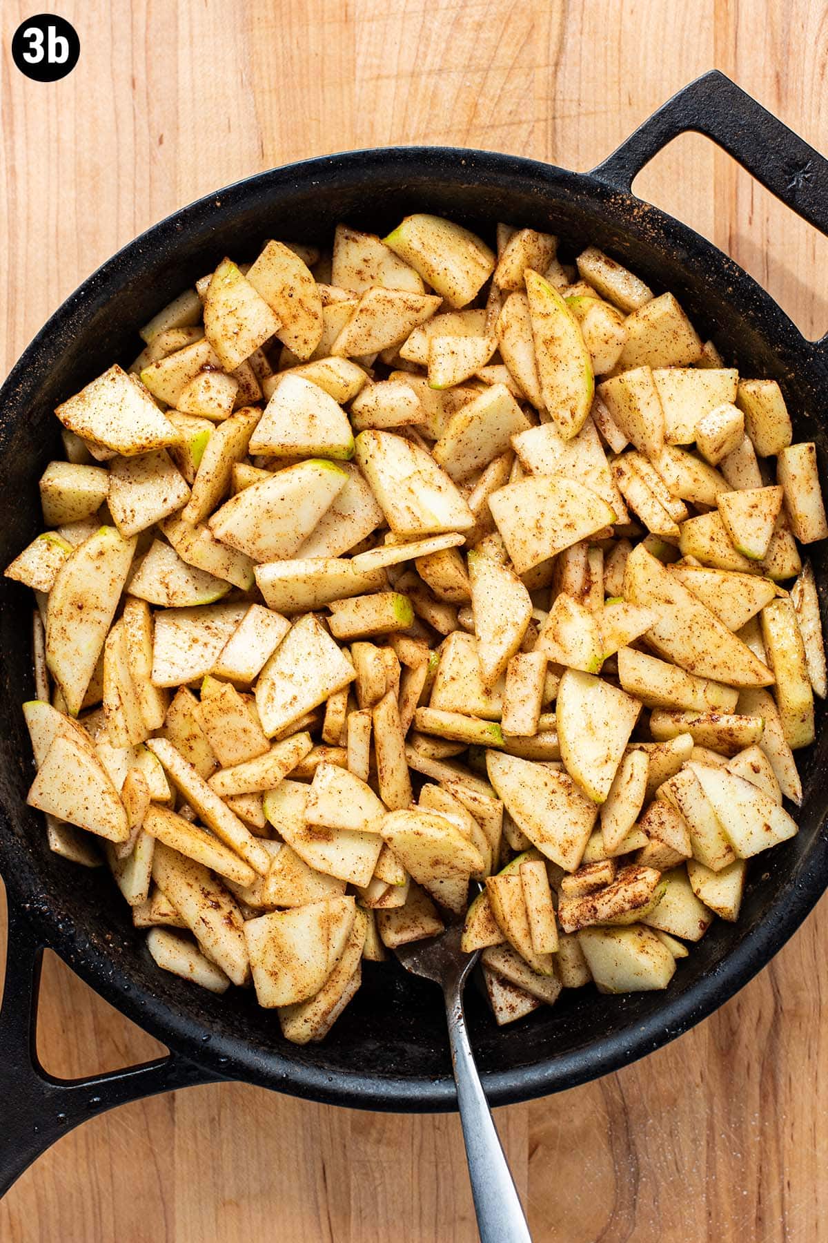 Sliced raw apples, sugar, and cinnamon in a cast iron skillet.