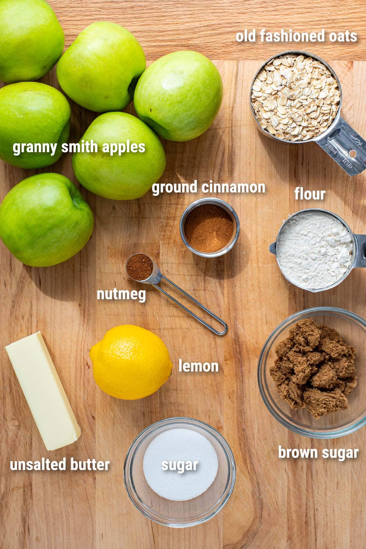 Raw ingredients for apple crisp laid out on a wooden cutting board.