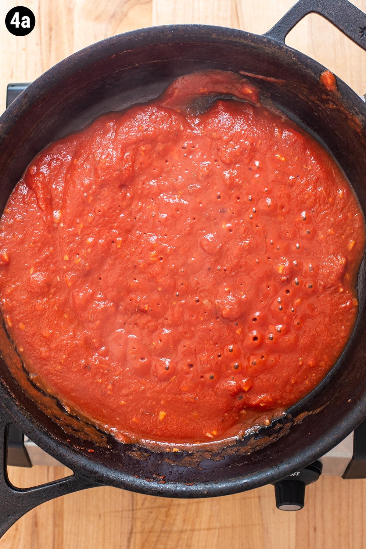 Tomato sauce simmering in a cast iron skillet.