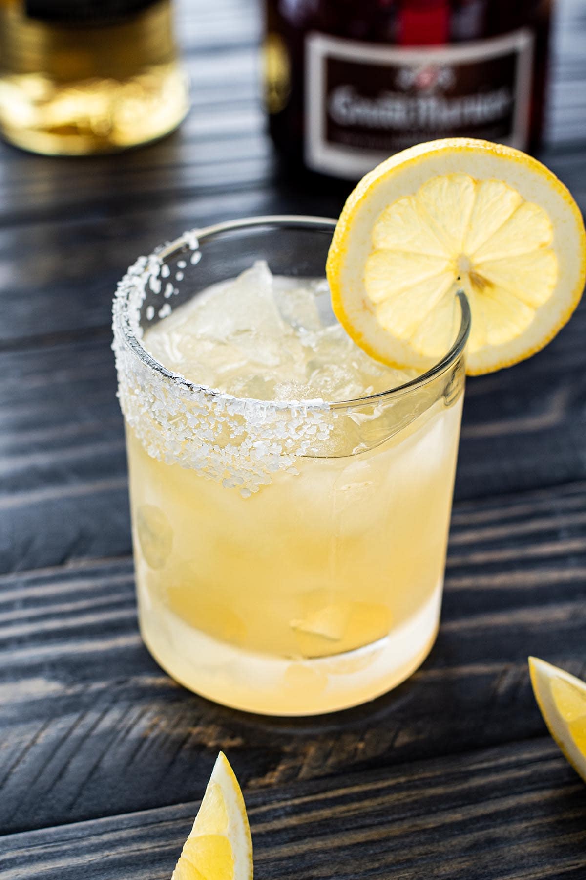 A golden margarita made with Grand Marnier with a salted rim and lemon wheel garnish.