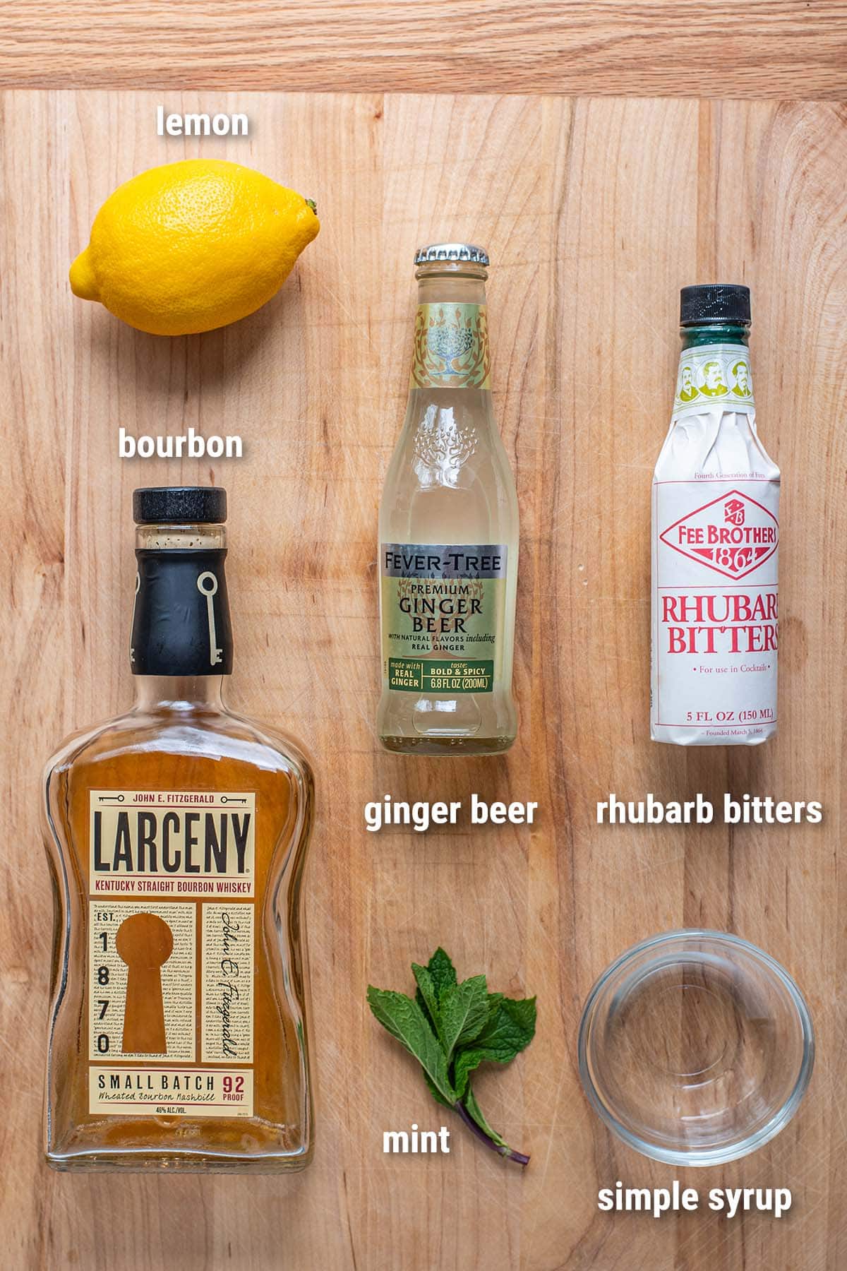 Bourbon lemonade cocktail ingredients laid out on a wooden cutting board.