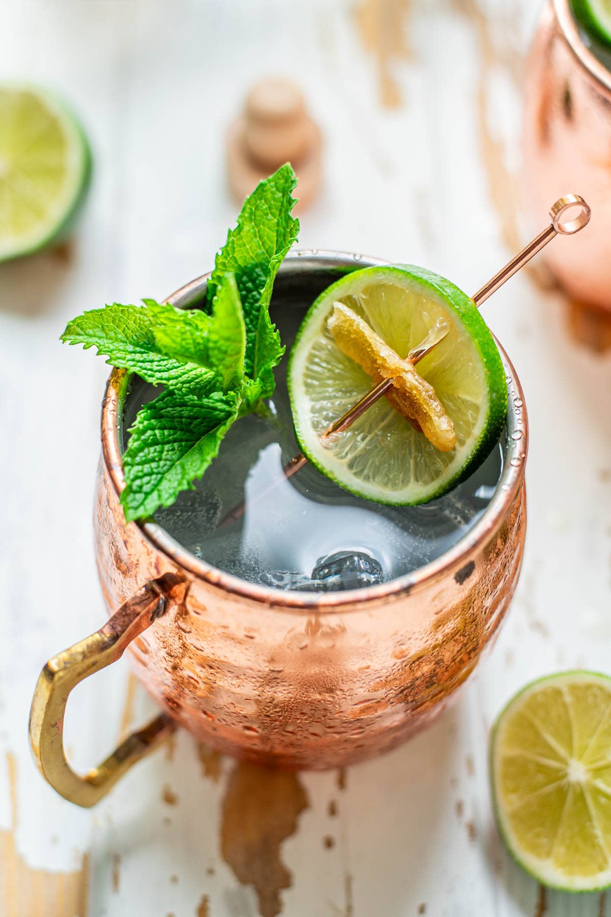 A Tequila Mule served in a copper mug garnished with mint leaves, a lime wheel, and candied ginger.