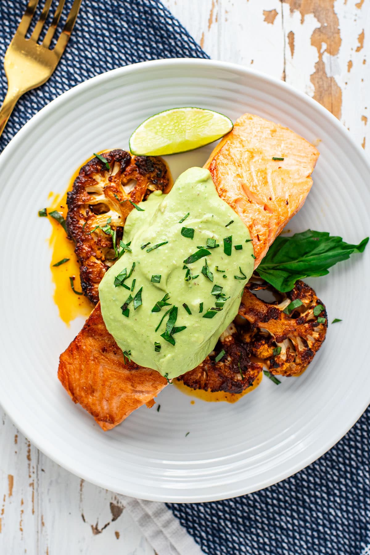 Pan-seared salmon topped with a creamy avocado sauce paired with deep-roasted harissa cauliflower.