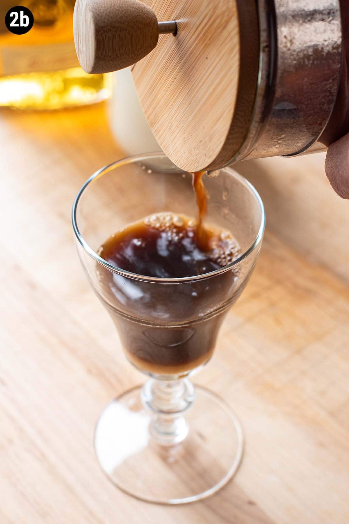 Pouring black coffee into a glass Irish Coffee cup