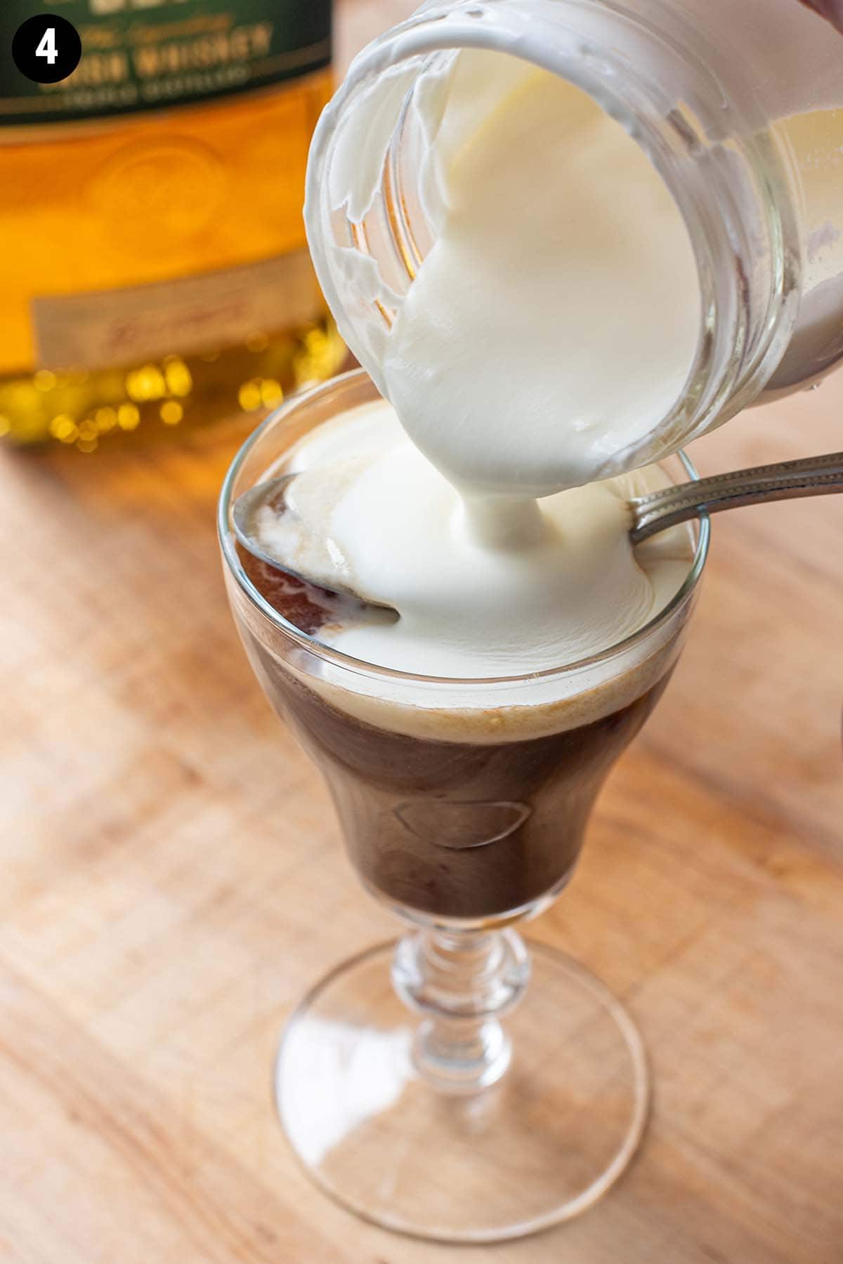 Pouring lightly whipped cream over an Irish Coffee as the finishing touch.
