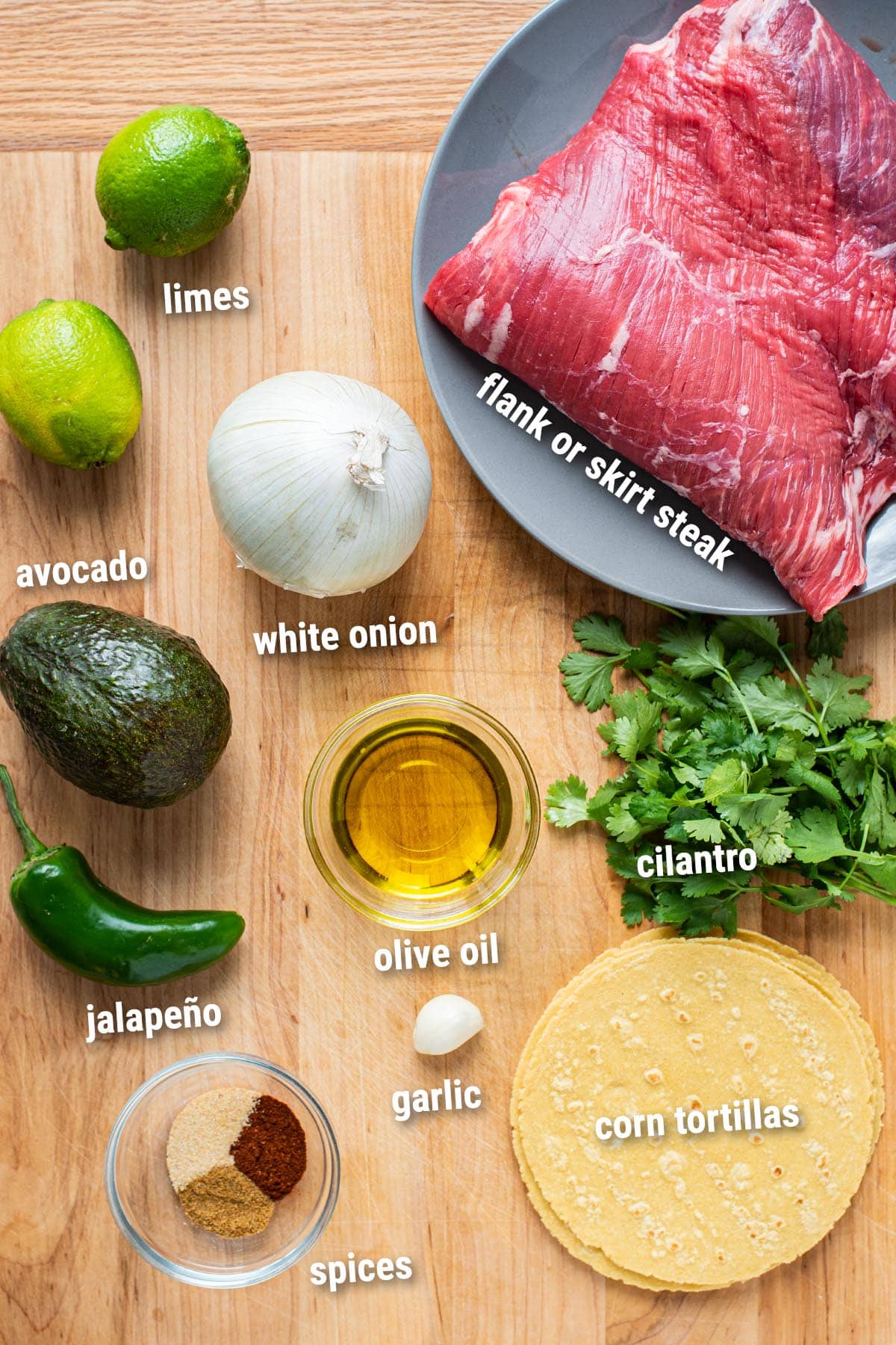 Raw, uncooked carne asada tacos ingredients laid out on a cutting board.