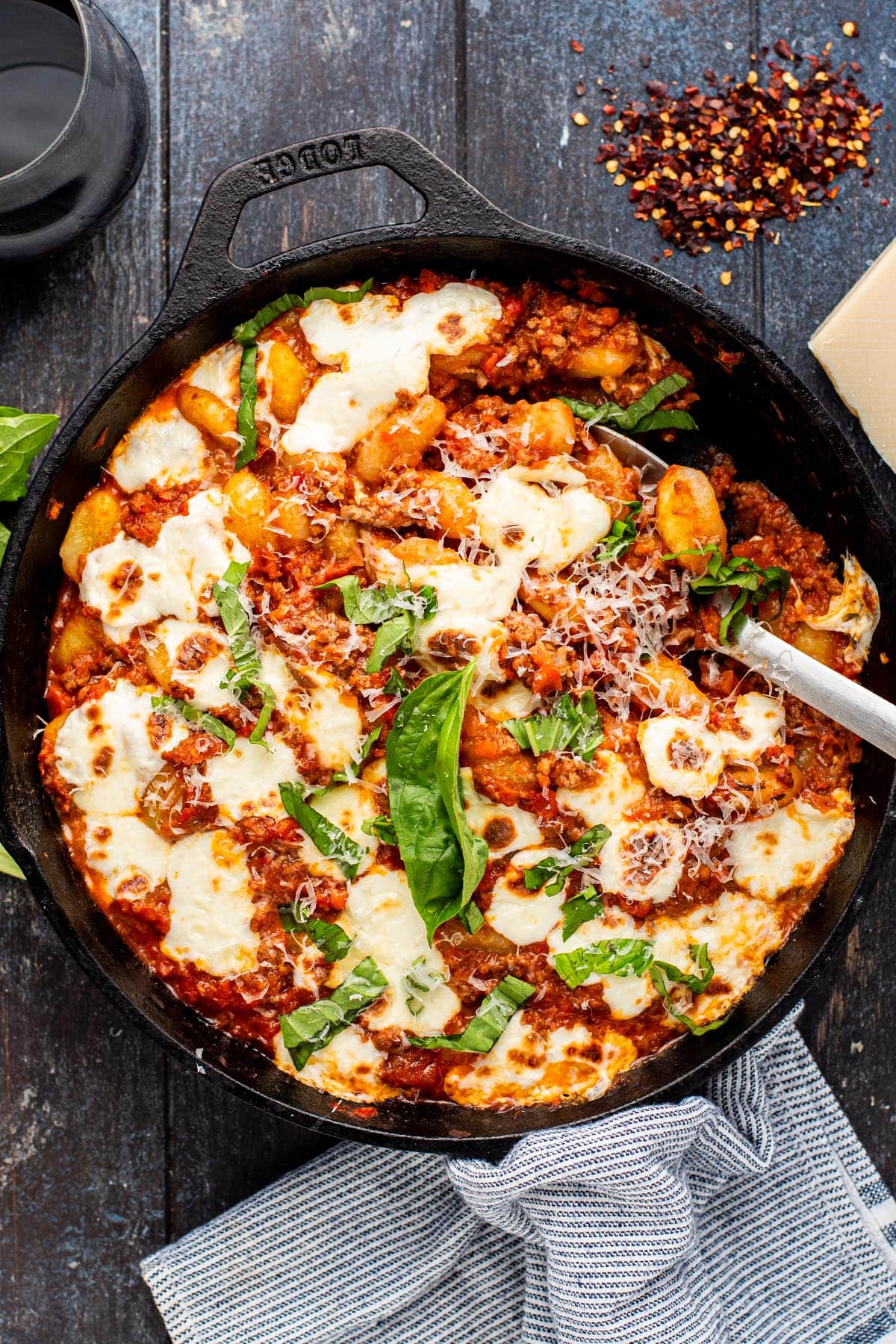 Golden baked gnocchi dish in a cast iron skillet topped with cheesy melted mozzarella and chopped basil.