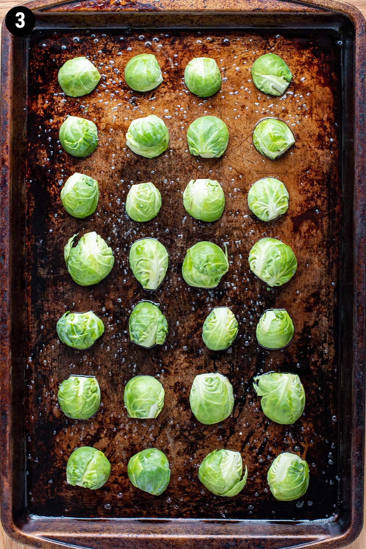 Uncooked brussels sprouts cut and arranged face side down on an oiled baking sheet.