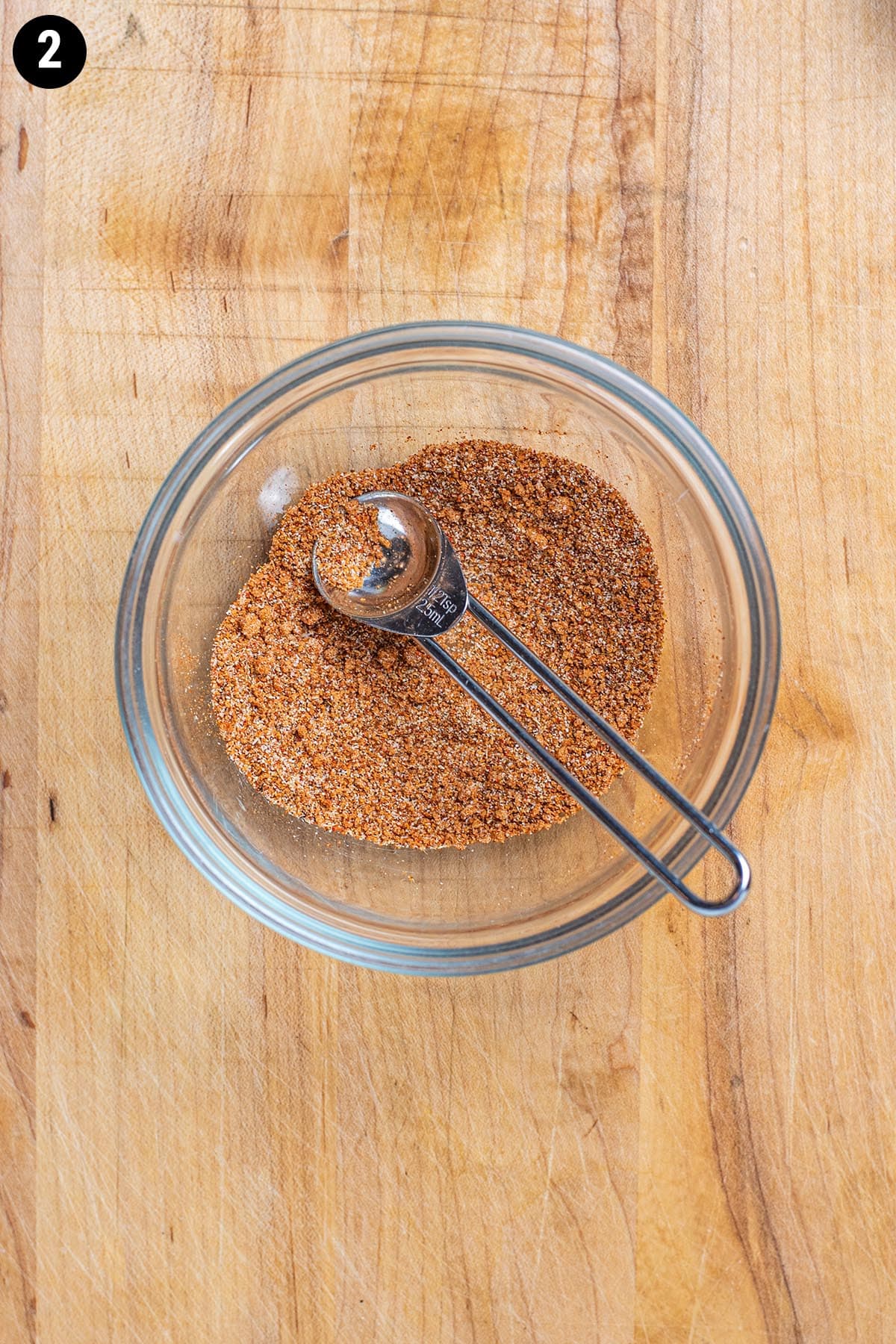 A blend of garlic powder, onion powder, paprika, cayenne pepper, brown sugar, and nutmeg in a small bowl.