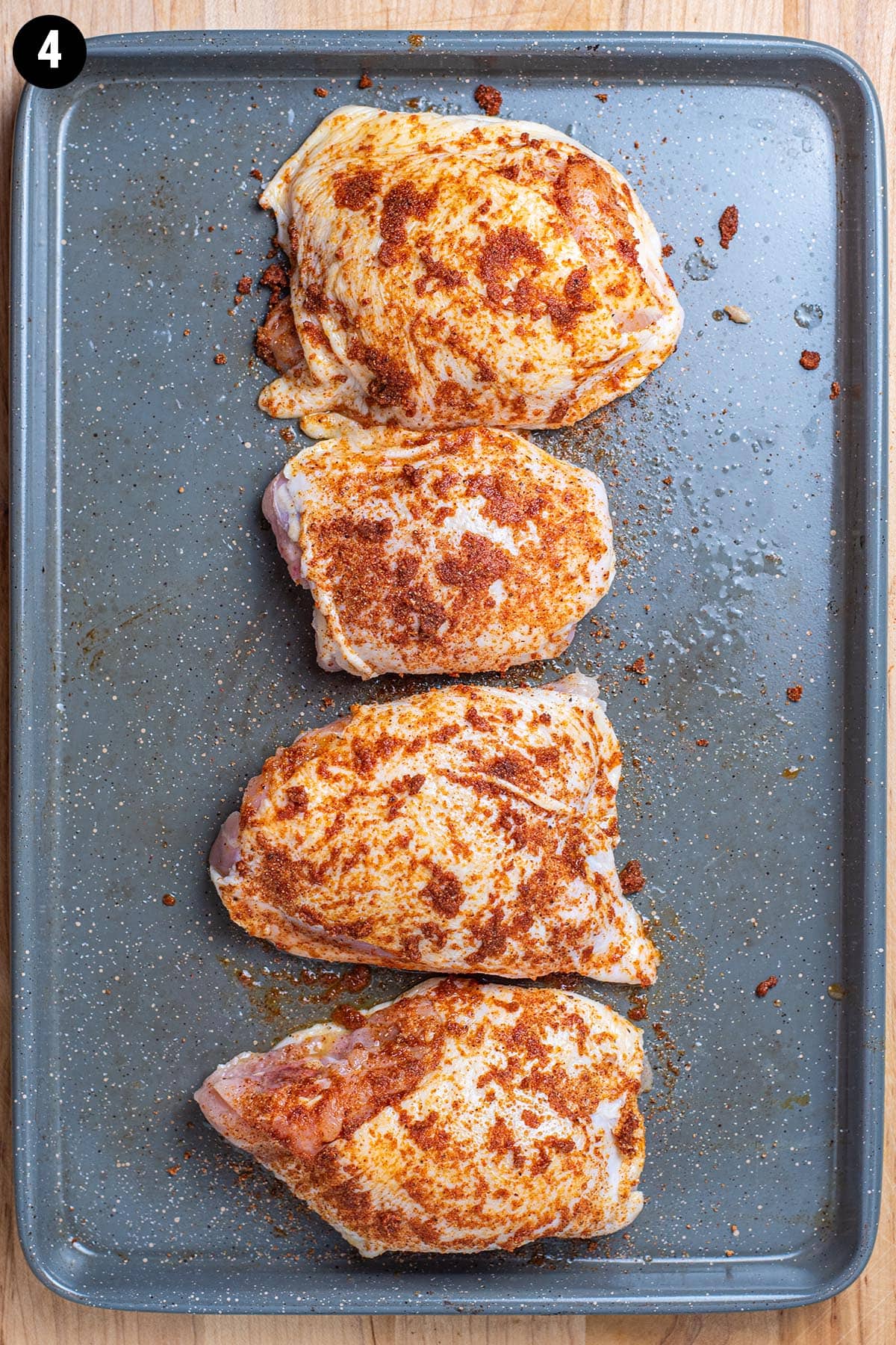 Raw, uncooked chicken thighs rubbed with a paste blend of dry spices.