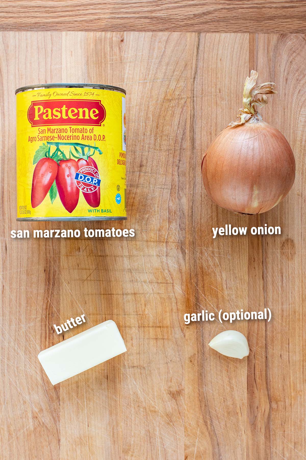 Raw, three-Ingredient tomato sauce ingredients laid out on a cutting board.