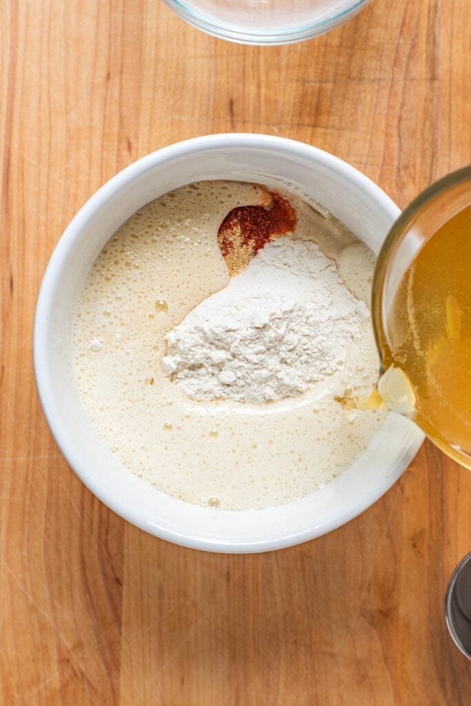 Mixing beer batter ingredients in a small white bowl.