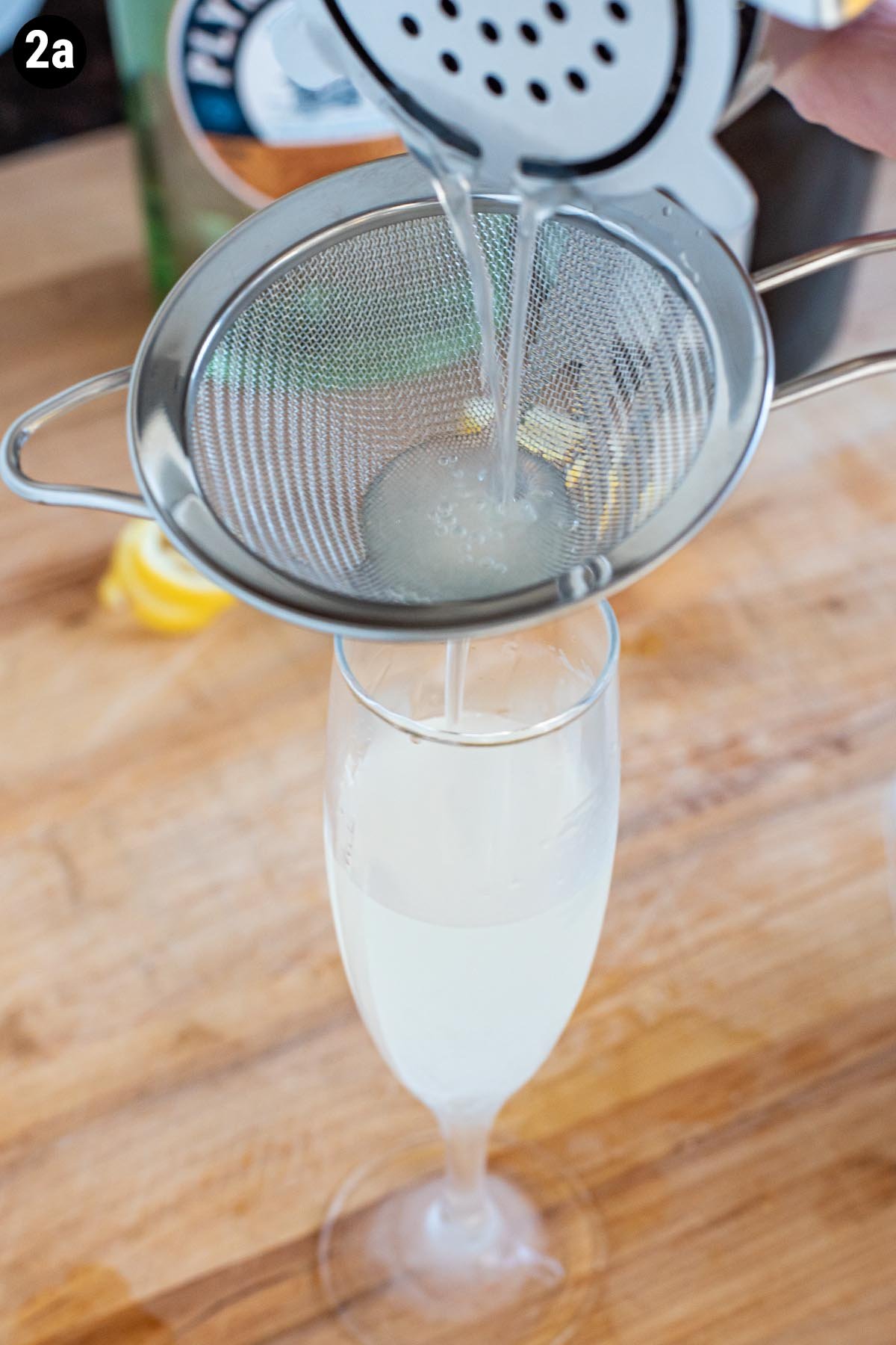 Double straining a French 75 cocktail into a chilled flute glass.