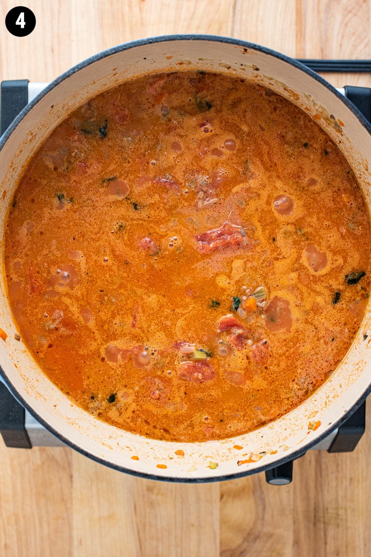Bolognese sauce in a Dutch oven with tomato, milk, and stock added before it has been simmered and thickened.