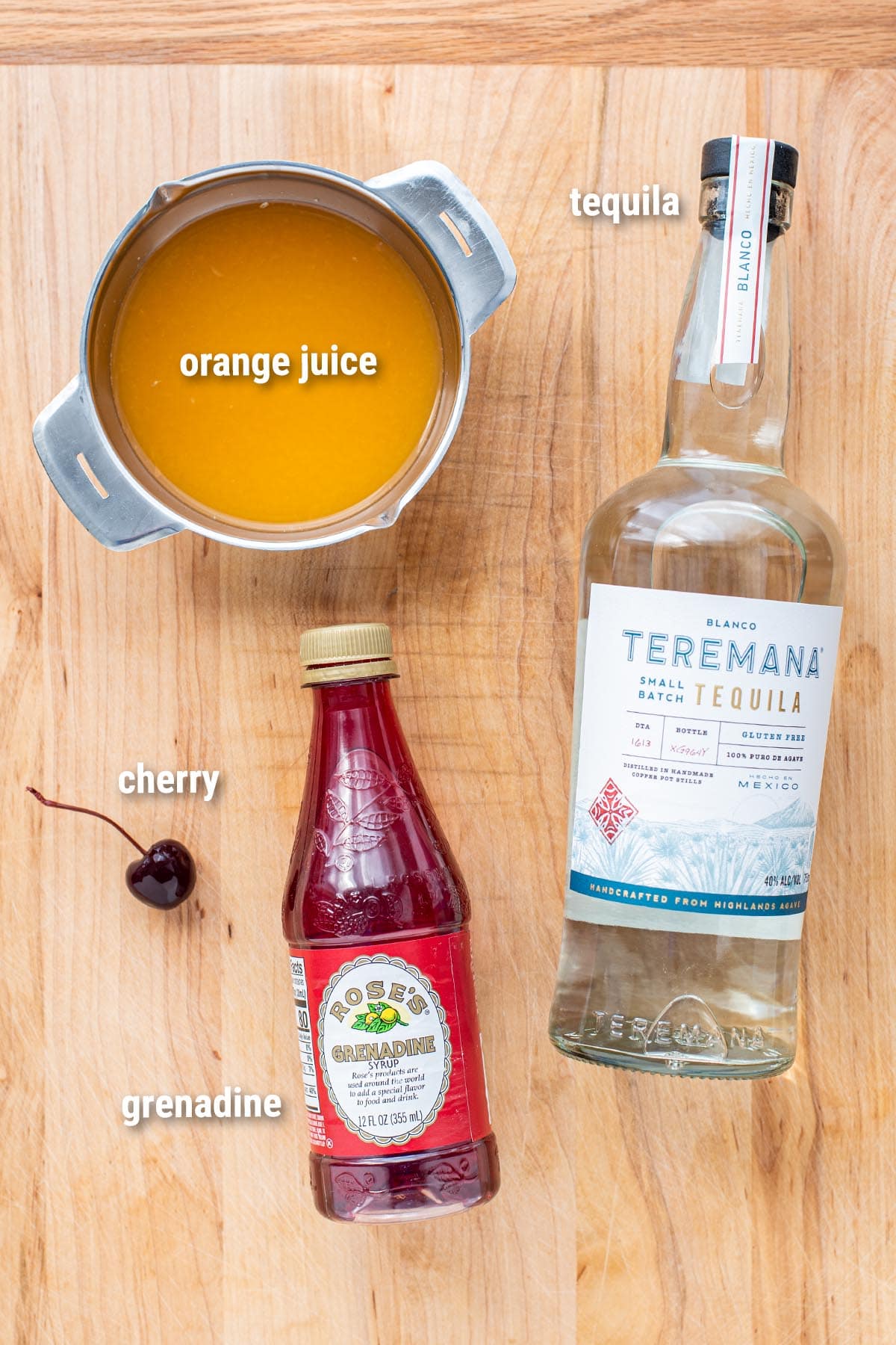 Tequila Sunrise cocktail ingredients laid out on a wooden cutting board.